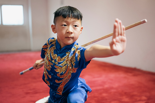 Young Chinese boy practising Wushu in a gym