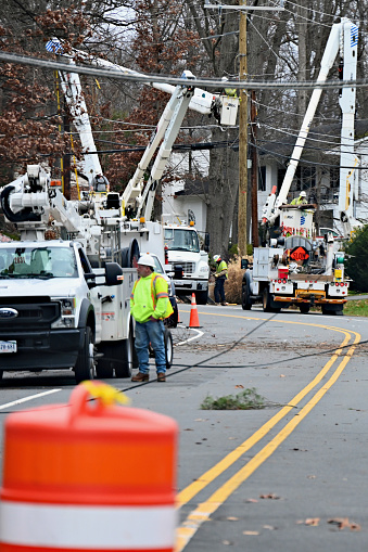 Fairfax, Virginia, USA - January 10, 2024: Several crews from Dominion Energy work together to restore power to a suburban neighborhood following damage to power lines caused by high winds and rains the night before.