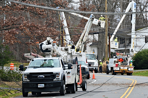 Fairfax, Virginia, USA - January 10, 2024: Several crews from Dominion Energy work together to restore power to a suburban neighborhood following damage to power lines caused by high winds and rains the night before.