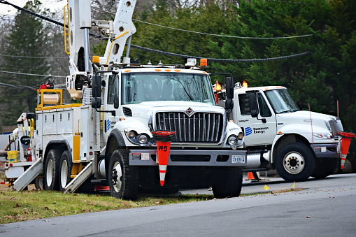 Fairfax, Virginia, USA - January 10, 2024: Several crews from Dominion Energy work together to restore power to a suburban neighborhood following damage to power lines caused by high winds and rains the night before.