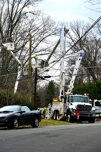 Fairfax, Virginia, USA - January 10, 2024: Several crews from Dominion Energy work together to restore power to a suburban neighborhood following damage to power lines caused by high winds and rains the night before.