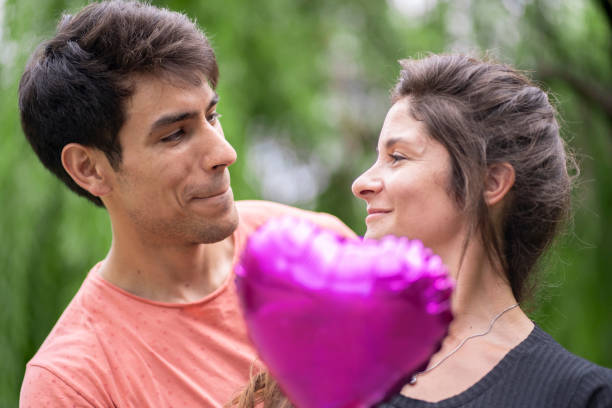istock Man surprising girlfriend with heart-shaped balloon. 1933947489