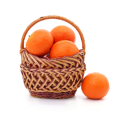 Wicker basket filled with oranges isolated on a white background.
