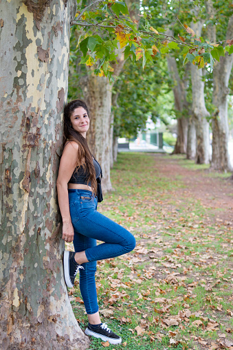 Woman posing in a park leaning on a tree