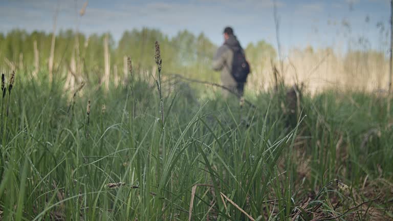 A man casts a spinning rod on the river bank.