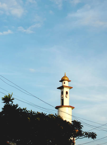 The mosque tower building with a bright blue sky background with white clouds makes it beautiful.