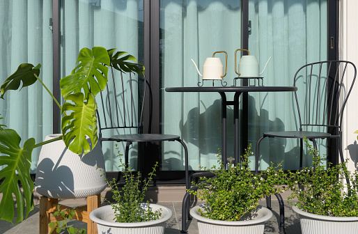Terrace with metal table and chairs in green garden at home