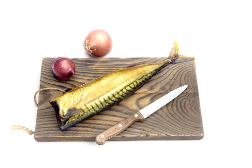 Knife, onion and one delicious, smoked headless mackerel on a cutting board on a white background close-up
