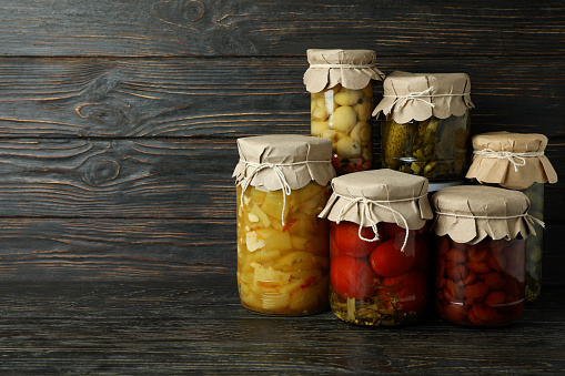 Jars of pickled vegetables on rustic wooden background