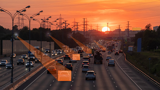 Sunset in a busy highway in the city, artificial intelligence detects intruders and controls the traffic situation, concept, selective focus, tinted image. Highway Traffic Camera With Artificial.
