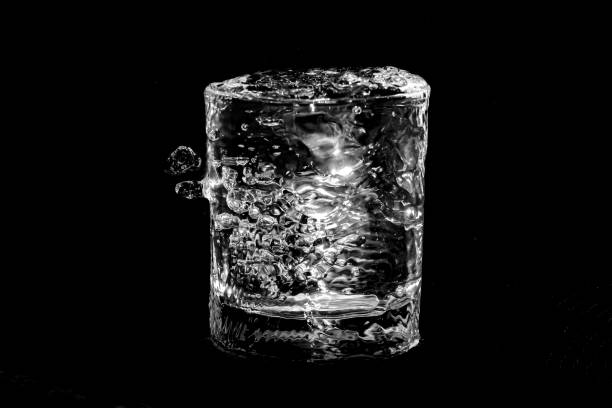 water overflowing and spilling from a glass isolated on a black background