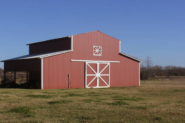 A picturesque red barn stands proudly on a farm, surrounded by hay bales and lush greenery, creating a serene rural atmosphere.