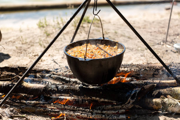 cooking pilaf over a campfire in a tent camp, rice, carrots, spices, mutton - vapours ストックフォトと画像