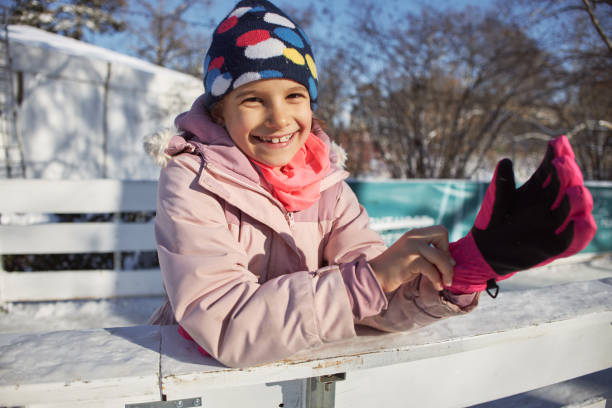 Portrait of smiling caucasian little girl of 6 7 years looking at camera outside in down coat and pink hat