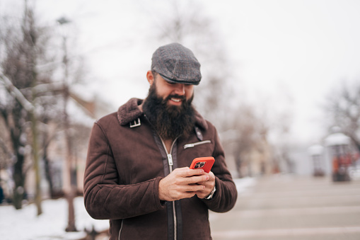 Bearded man using smart phone in the city