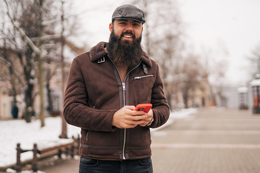 Bearded man using smart phone in the city