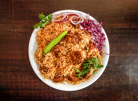 Bannu beef pulao rice with salad, onion and cabbage served in plate isolated wooden background top view indian spices and pakistani food