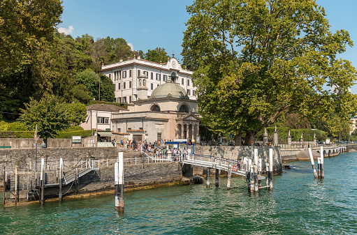 Tremezzina, Lombardy, Italy - September 5, 2022: The pier of the villa Carlotta in Tremezzina village with tourists are waiting for the ferry boat for sightseeing on Lake Como.