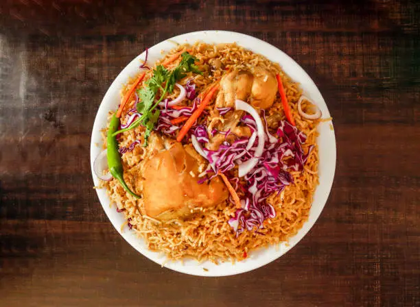 Spicy Chicken pulao with onion and cabbage served in plate isolated wooden background top view indian spices and pakistani food