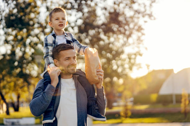istock A happy dad carrying his son on shoulders and giving him a popcorn while walking in neighborhood. 1934242892