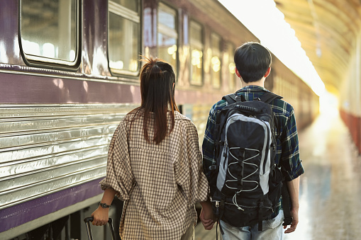 Rearview of young couple walking at the train station platform. Travel and vacations concept.