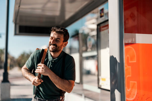 istock A happy young man is standing at bus stop and waiting for a bus. 1934274270