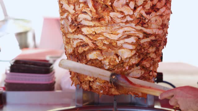 The cook cuts meat for shawarma on a skewer, fastfood