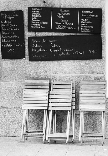 Cambados, Spain - January 26, 2020: facade of a restaurant with folded wooden tables and an offer of various typical dishes of the area.