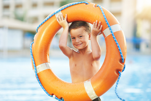 Picture of young boy holding lifebuoy at pool. High quality photo