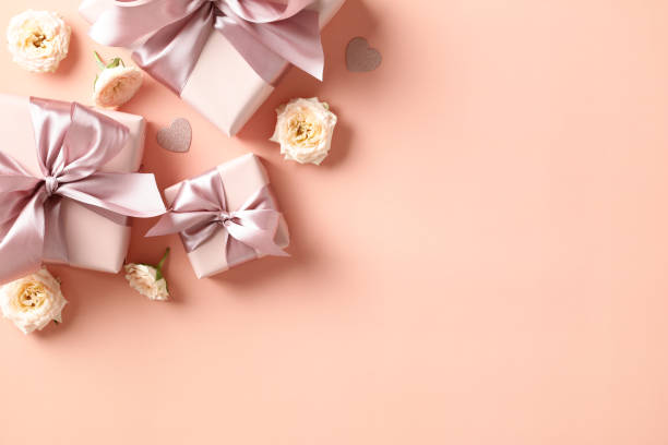 istock Valentine's Day flat lay composition. Top view pink gift boxes with ribbon bow and rose flowers on beige desk table. 1934309427
