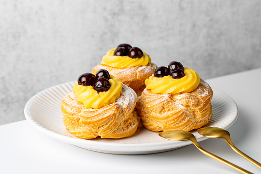 Zeppole di San Giuseppe, zeppola - baked puffs made from choux pastry, filled and decorated with custard cream and cherry.  Italian pastry traditional for Saint Joseph's Day.
