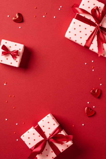 istock Valentine day vertical banner. Flat lay composition with gift boxes and red hearts on red background. Top view. 1934321898
