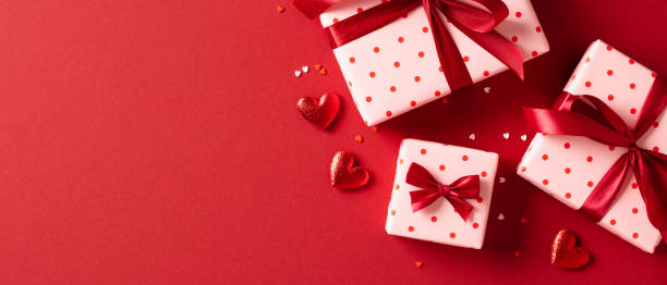 Valentines Day banner design. Top view gift boxes with red ribbon bows, hearts, confetti on red background stock photo