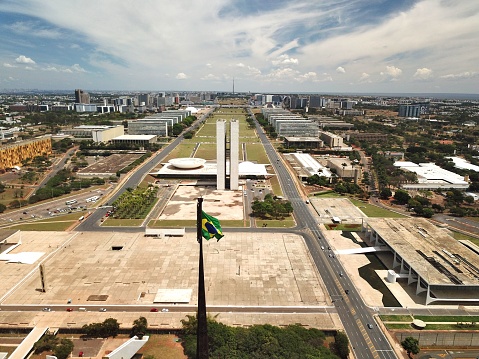 An aerial view of Brasilia's Esplanade of Ministries with the Brazilian flag in the foreground.