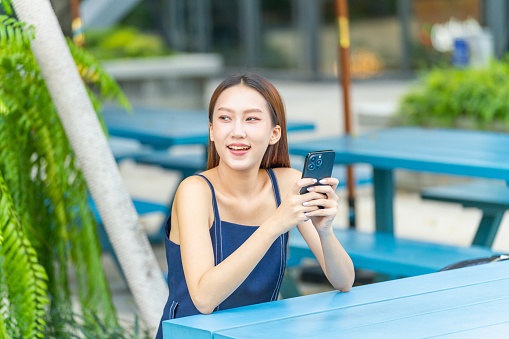 Remote Work Oasis: Asian Woman Using Phone at an Outdoor Park
