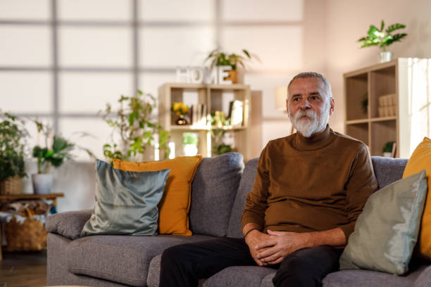 istock Mature man sitting on the sofa, looking away, contemplating 1934341038