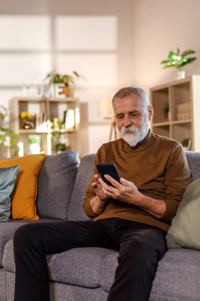istock Mature man sitting on the sofa, using his smart phone 1934341041