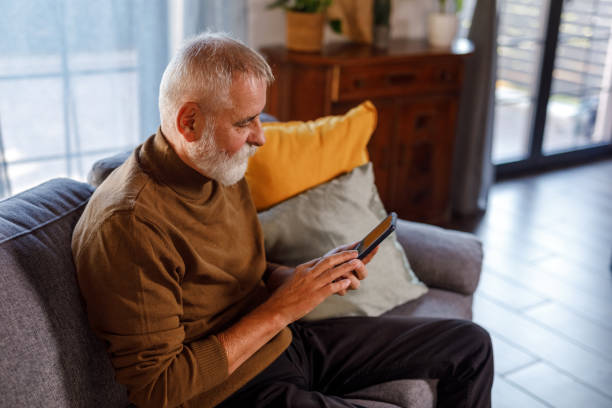 istock Mature man sitting on the sofa, using his smart phone 1934341046
