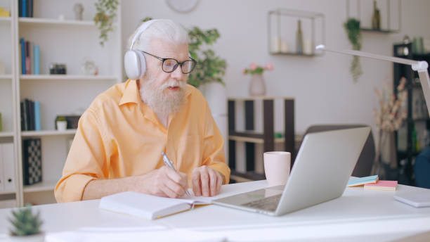 istock Senior man converses with his online tutor, dedicatedly studying at home as a mature student 1934347499