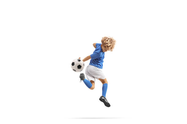 Boy kicking a football with backheel isolated on white background