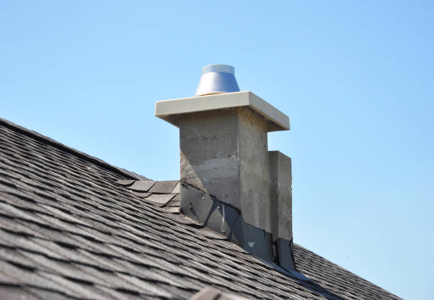 A close-up image of a brick chimney on a clay tiled roof during a beautiful sunset. The contrast between the rustic architecture and the glowing sky creates a sense of nostalgia and warmth.