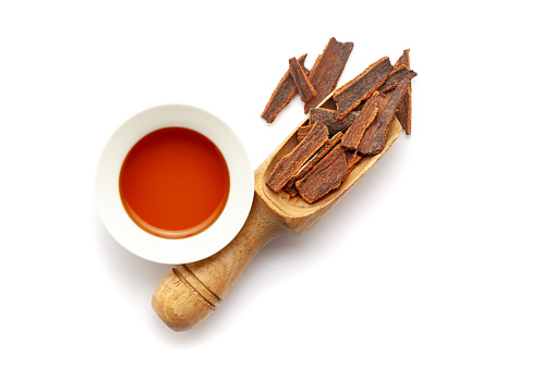 Top view of Dry organic Cinnamon sticks (Cinnamomum verum), in a wooden scoop along with its essential oil.