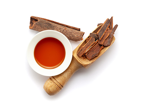 Top view of Dry organic Cinnamon sticks (Cinnamomum verum), in a wooden scoop along with its essential oil.