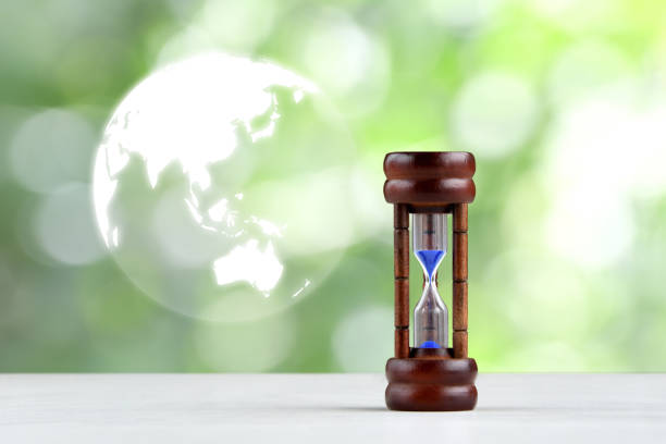istock Hourglass and earth shape on natural green background 1934350892