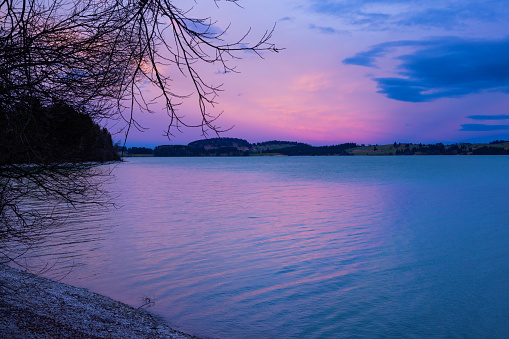 Forggensee during a winter twilight when the blu color mixes with pink and purple for a splendid blue hour scene