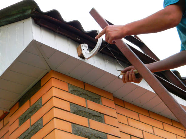 istock A building contractor is installing rain gutter system, fitting brackets on the top of fascia board, setting up a level line string for the correct positioning of the rain gutter. 1934357743