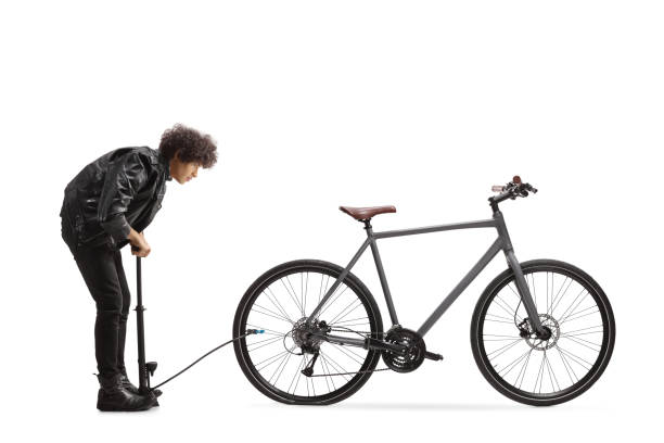 istock Full length profile shot of a guy pumping a flat bicycle tire 1934370594