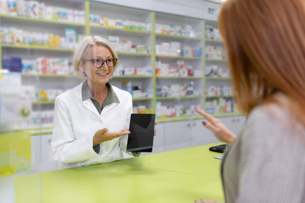 istock Happy mature technician showing plans to her customer on touchpad in a pharmacy 1934374291