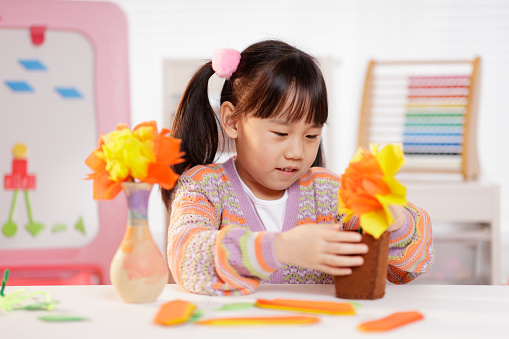 Little girl lying on the background of various colourful plastic and wooden toys. Childhood concept. Top view, flat lay.