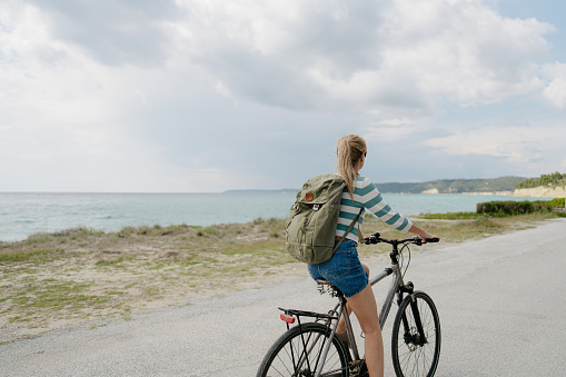 Photo of a young woman exploring the coastline on a bicycle